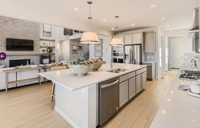 Open concept kitchen in a new Century Communities home at Trails at Smoky Hill in Parker, Colorado featuring light cabinetry, quartz island, and stainless steel appliances.