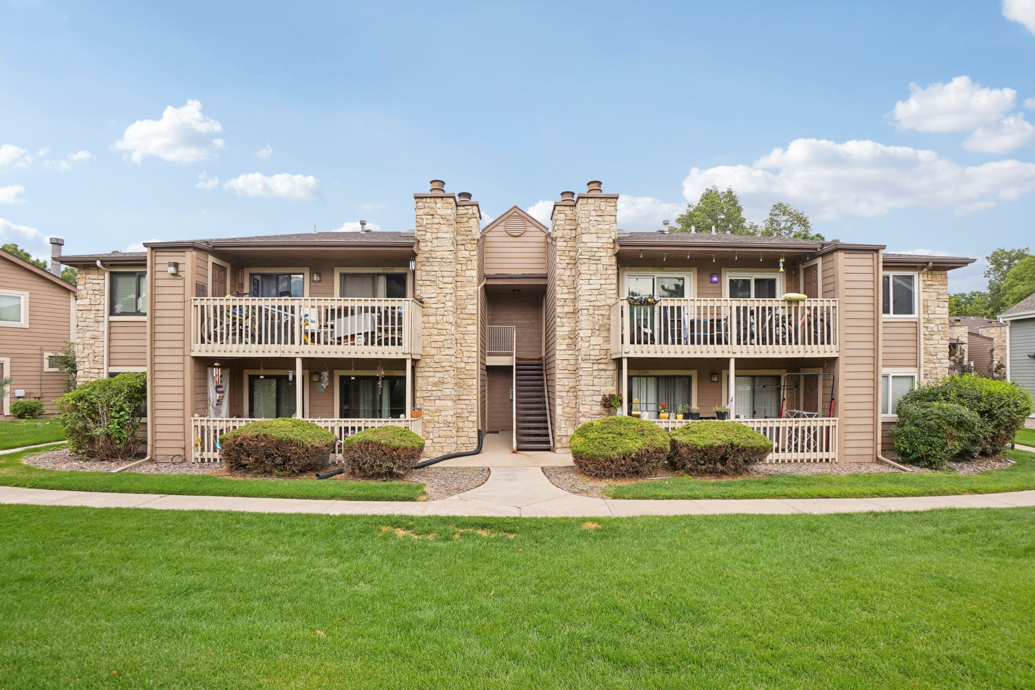 Exterior of Englewood CO condo for sale with balconies, stone accents, and landscaped grounds