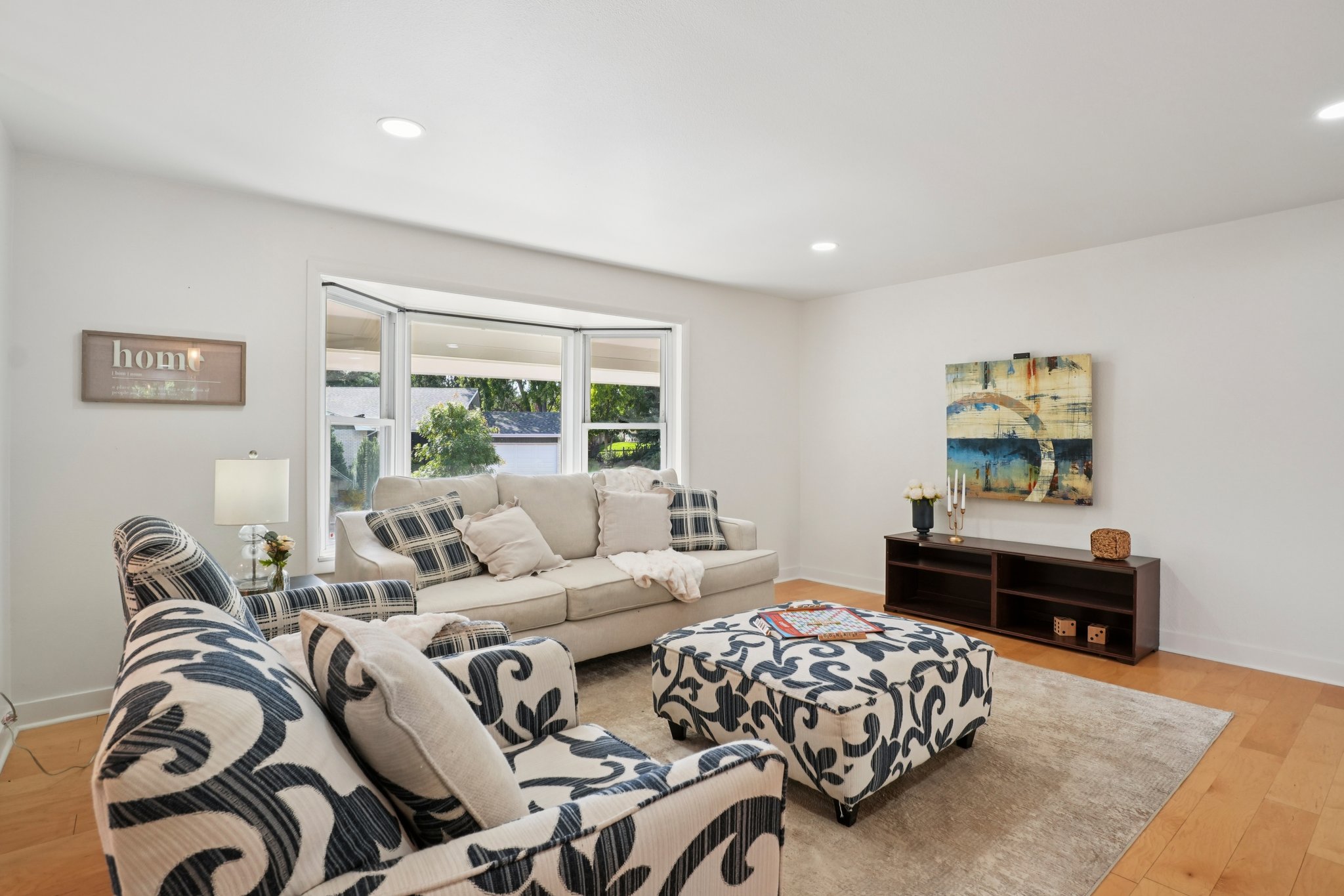 Staged living room at 3785 S Benton Way Denver featuring neutral sofa, patterned chairs, large window, and modern décor.