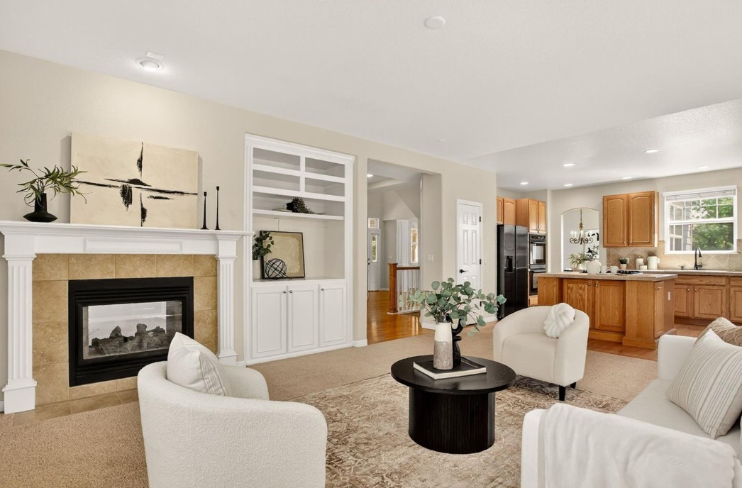 Open-concept living room with fireplace and kitchen in a Saddle Rock Aurora Colorado resale home featuring modern updates and natural light.