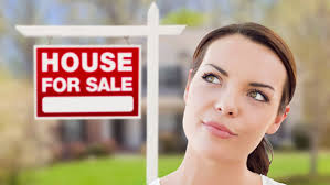 Colorado homeowner considering FSBO sale while standing near a For Sale sign